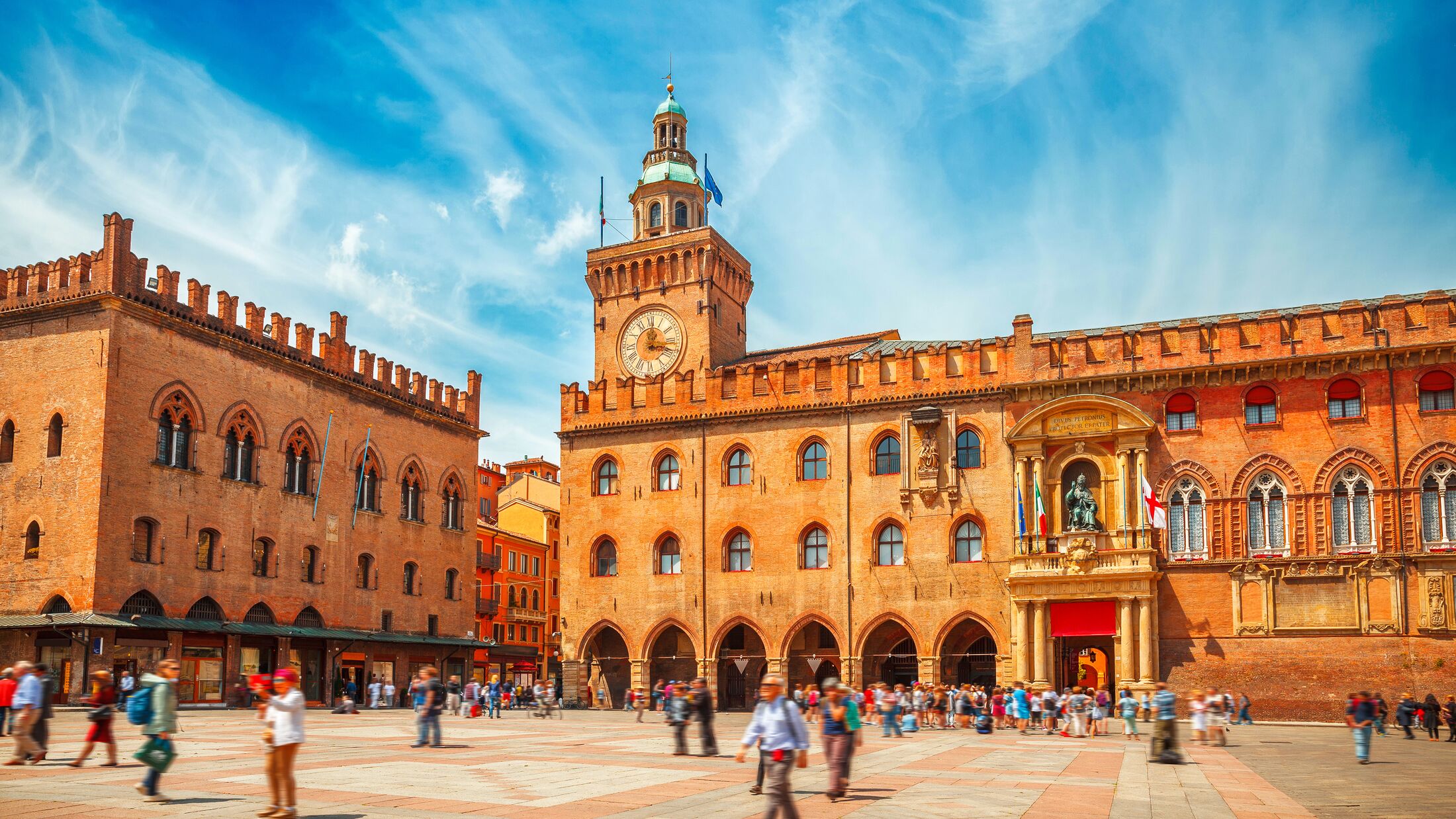 Italy Piazza Maggiore in Bologna old town tower of hall with big clock and blue sky on background. Antique buildings terracotta galleries