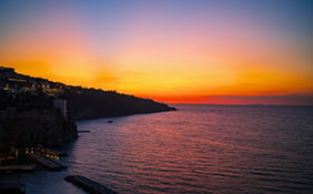 Aerial view of coastline Sorrento city and Gulf of Naples with colorful sunset sky