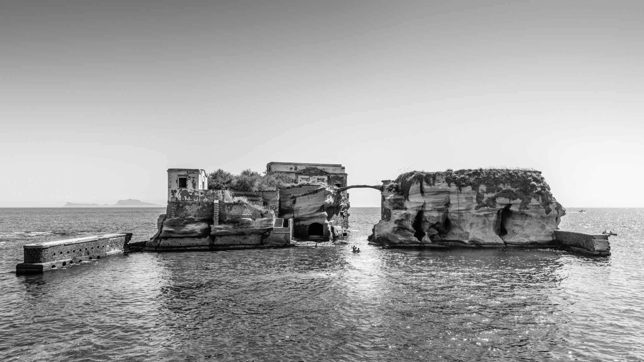 The Gaiola Island, one of the minor islands of Naples, a coastal scenery close to the Underwater Park of Gaiola, a protected marine area. Some boys take a swim by the rocks.