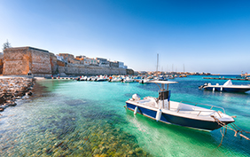 Several fishing boats at the Otranto harbour - coastal town in Puglia with turquoise sea. Italian vacation. Town Otranto, province of Lecce in the Salento peninsula, Puglia, Italy