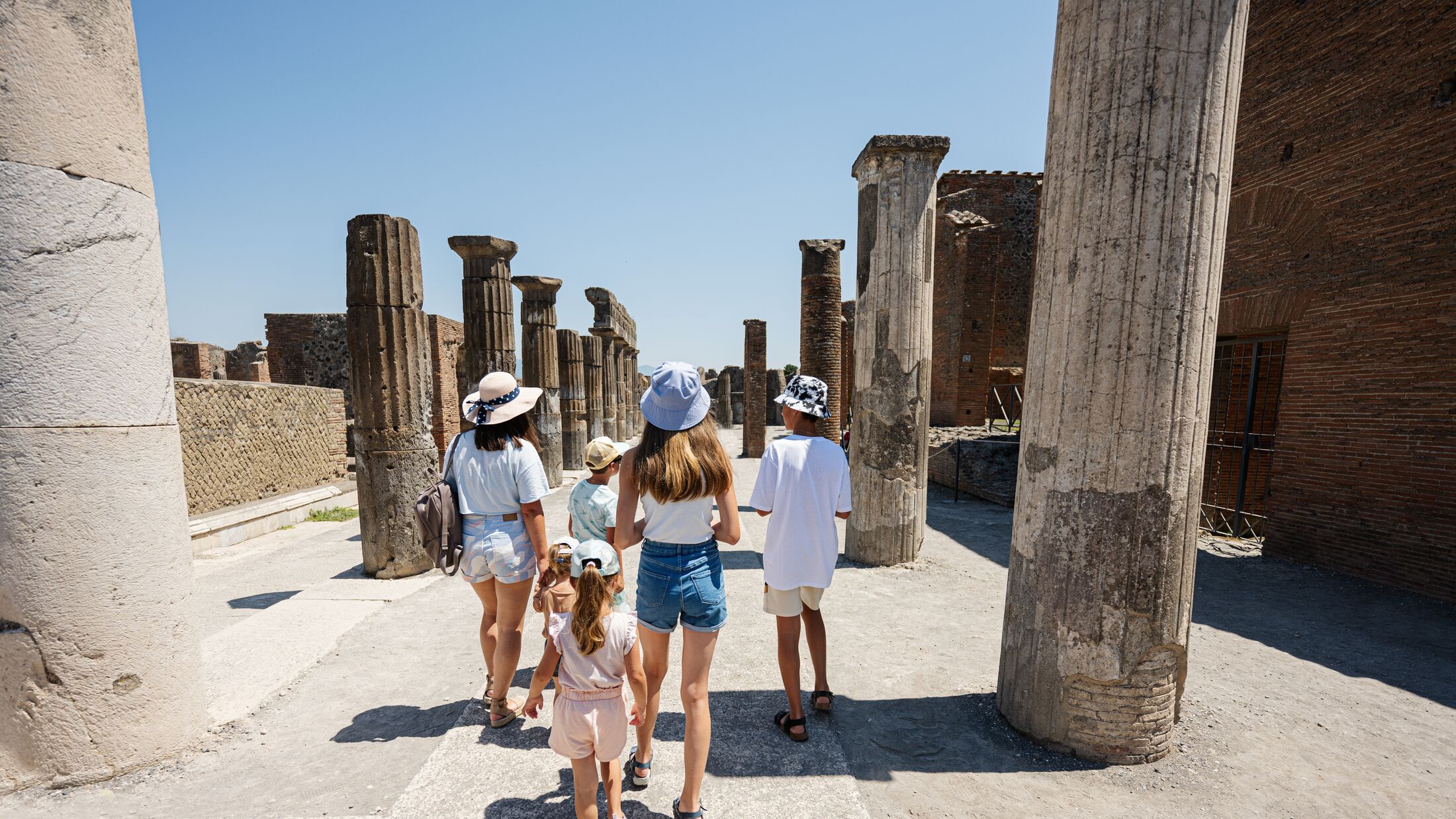 Back of family tourist walking at Pompeii ancient city, Italy.