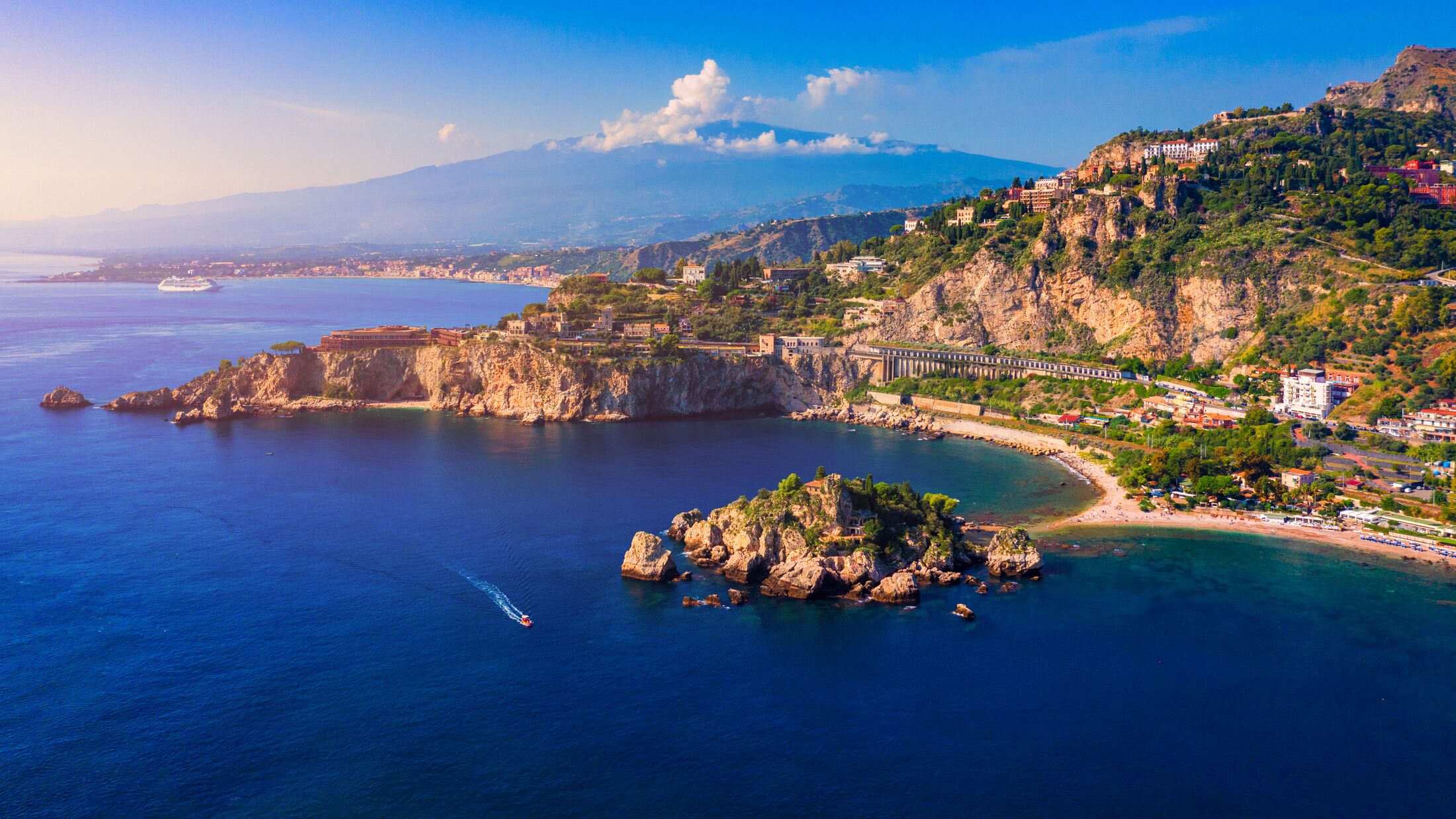 Taormina is a city on the island of Sicily, Italy. Mount Etna over Taormina cityscape, Messina, Sicily. View of Taormina located in Metropolitan City of Messina, on east coast of Sicily island, Italy.