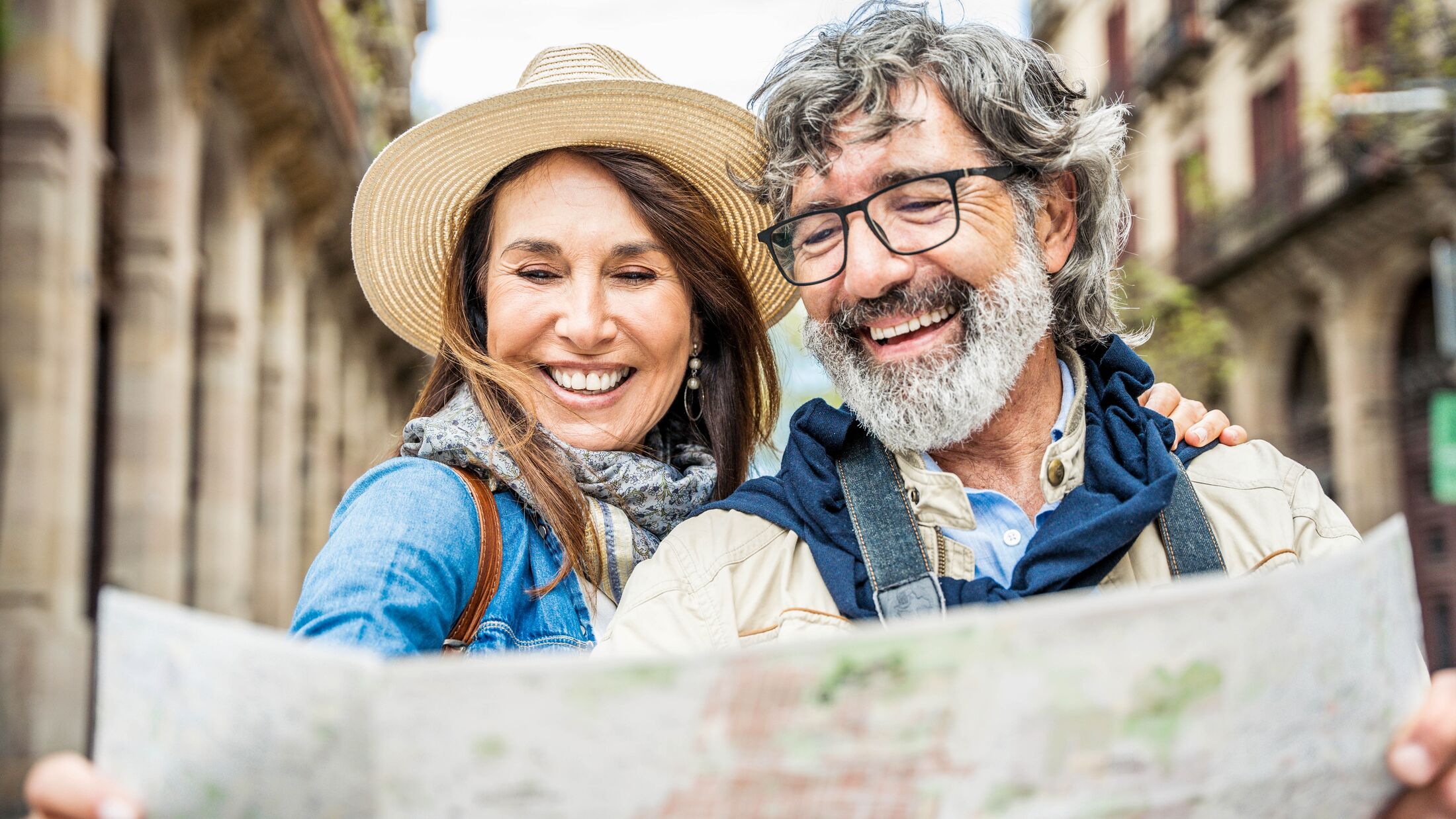 Married couple of tourists sightseeing city street with map - Happy husband and wife enjoying summer vacation together - Touristic life style concept with aged woman and man traveling European city