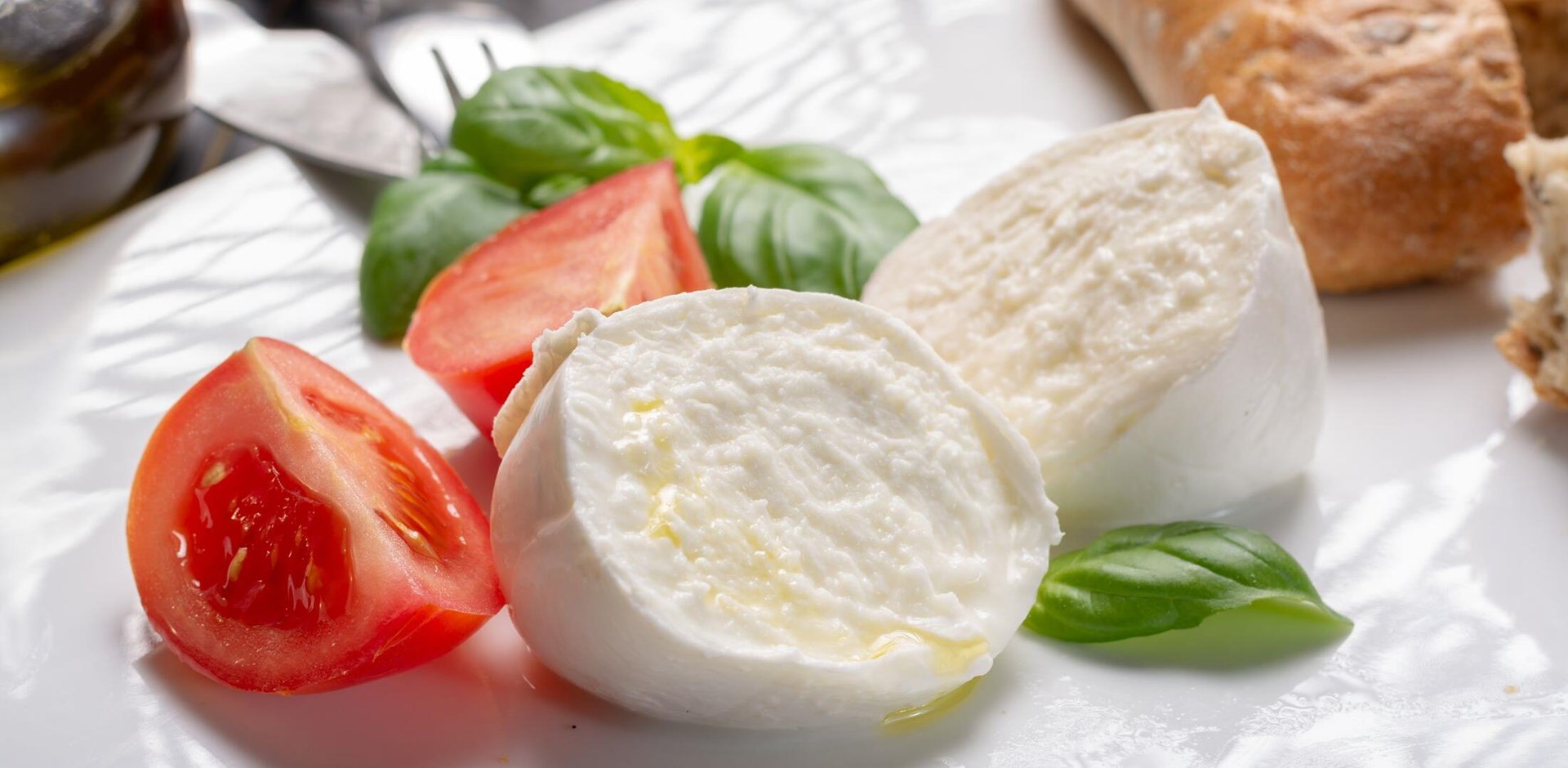 Traditional italian food - white ball mozzarella buffalo Italian soft cheese with cheese knife, tomato, basil, olive oil