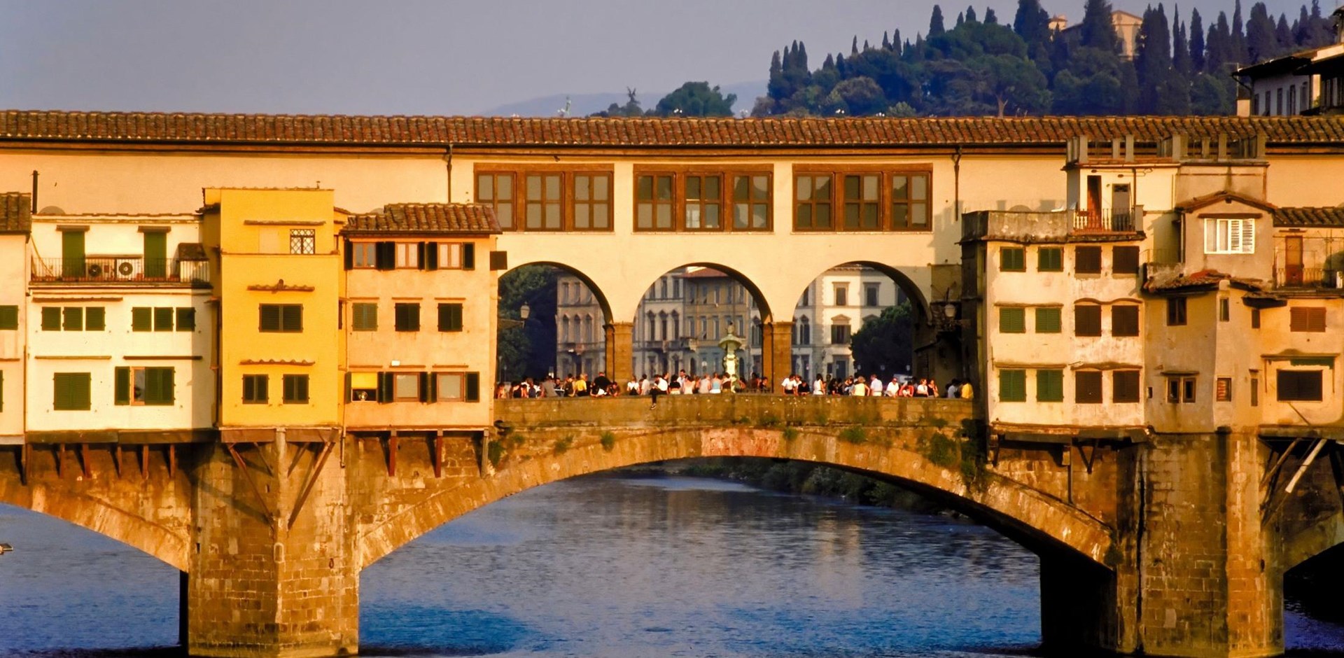 Ponte Vecchio over a body of water with a city in the background