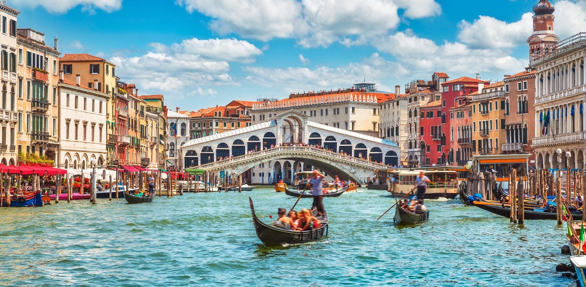 Bridge Rialto on Grand canal famous landmark panoramic view Venice Italy with blue sky white cloud and gondola boat water.