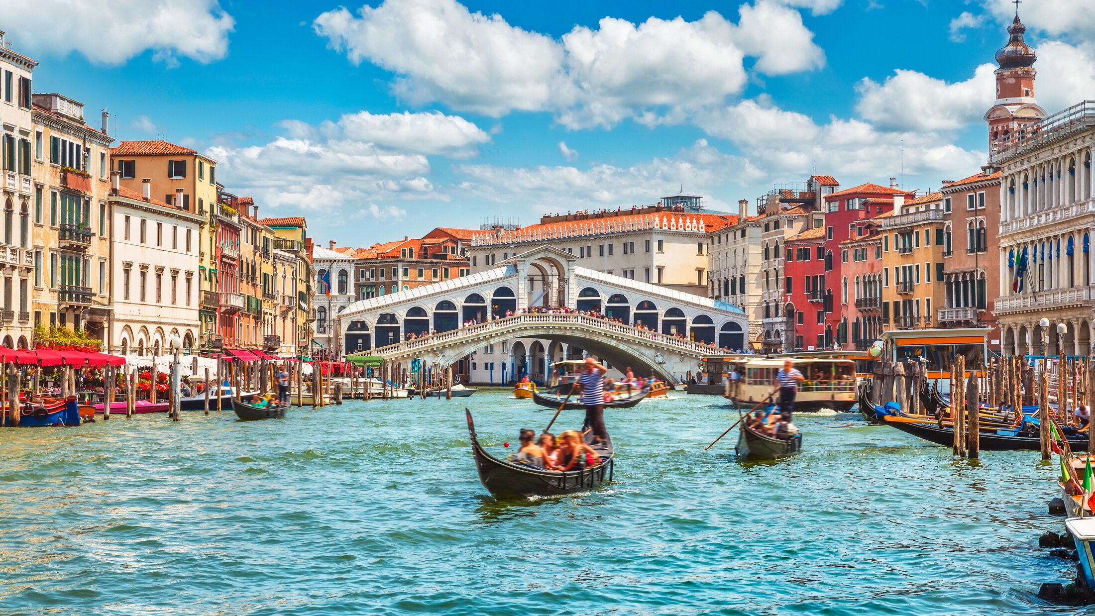 Bridge Rialto on Grand canal famous landmark panoramic view Venice Italy with blue sky white cloud and gondola boat water.