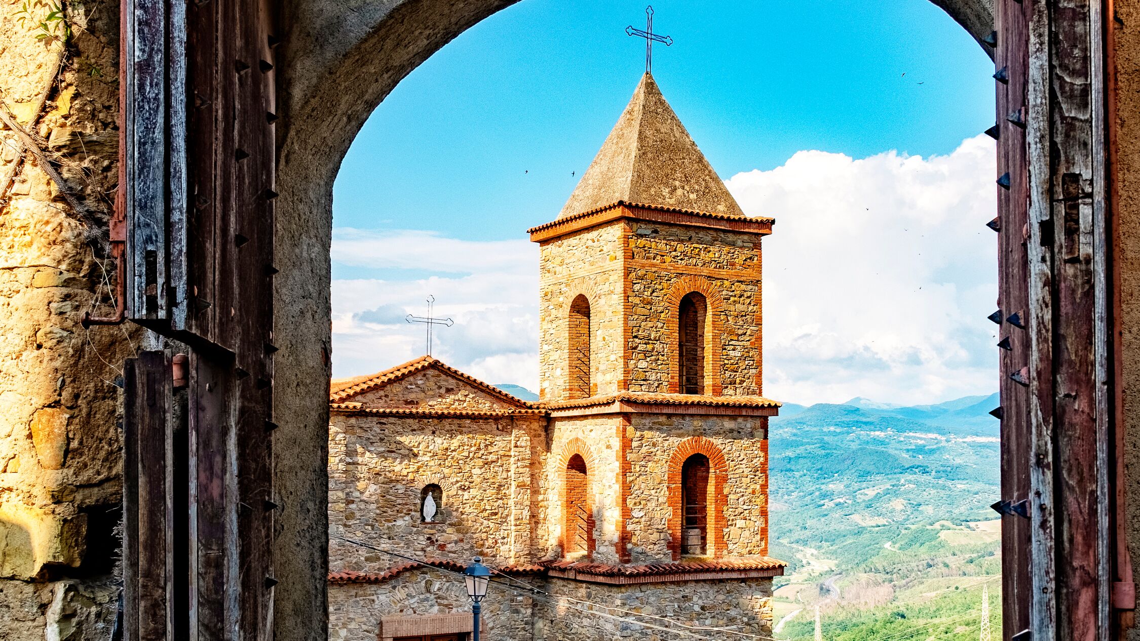 Picturesque shot of historic village Castelnuovo at the Cilento national reserve in Italy. The medieval door opens for its historic church.