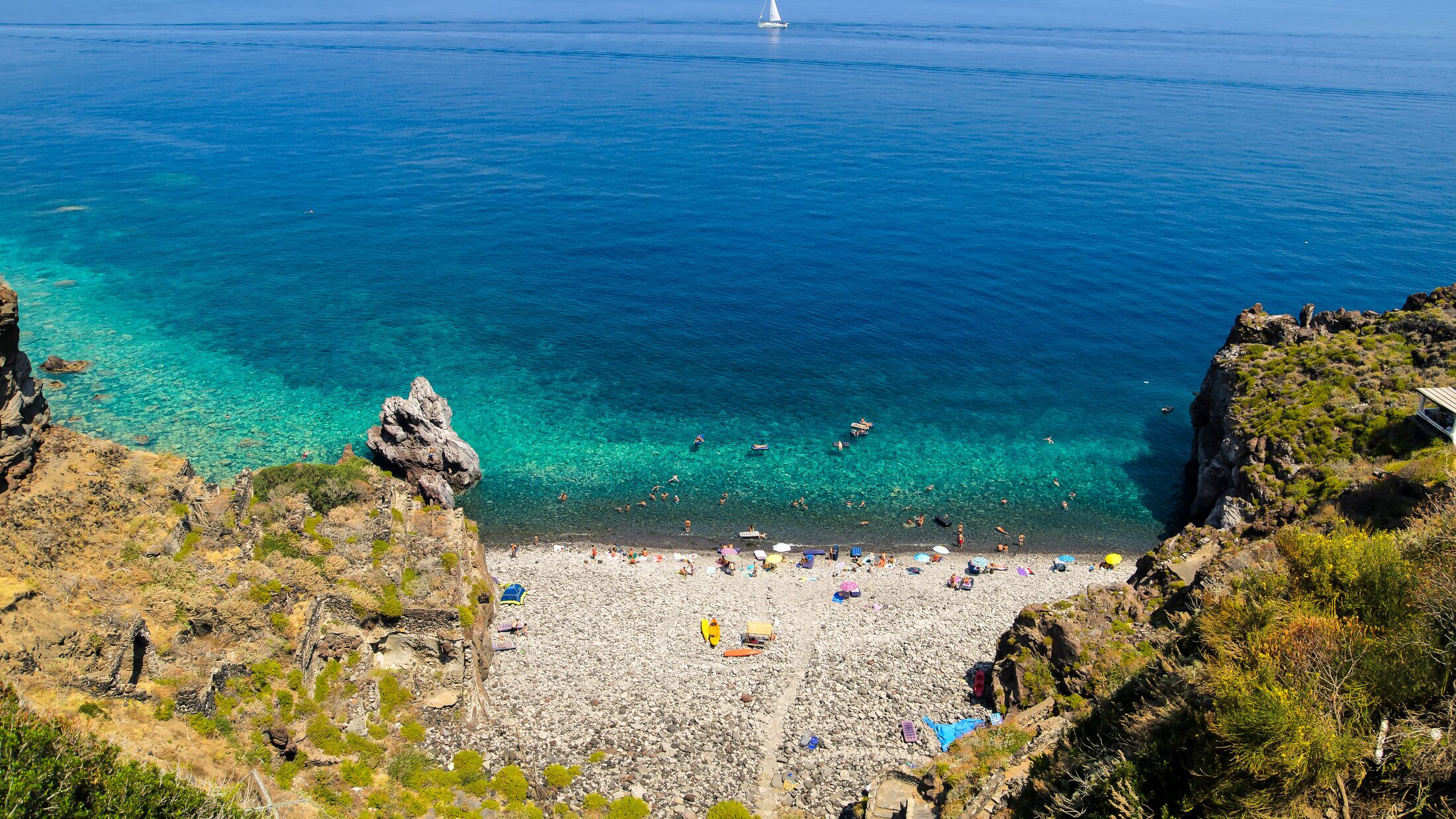 Aerial view of the crystal clear sea water at Spiaggia dello Scario beach in Malfa, Salina, Aeolian Islands. People enjoy the sun and sand on a clear summer day. Beautiful holiday destination.
