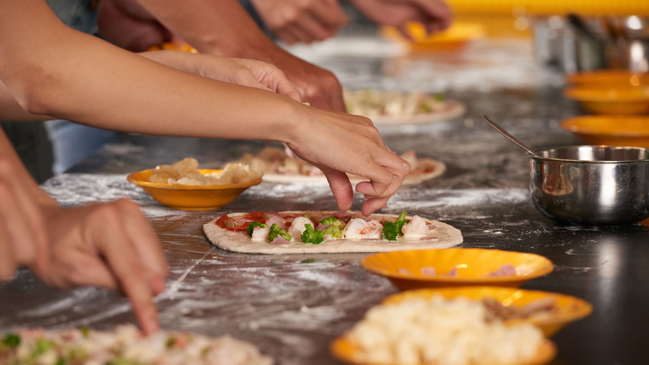 Hands of people making pizzas together