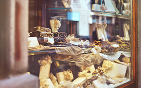 Rich variety of chocolates, candies and biscuits with a gift box in display window of italian pastry shop at the street of Florence city