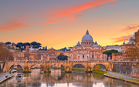 cityscape and panoramic view of old bridge with warm sunset sky water reflections and dome of St. Peters cathedral church with old buildings and architecture in Rome, Italy