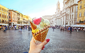 Italian ice - cream cone held in hand on the background of Piazza Navona in Rome , Italy