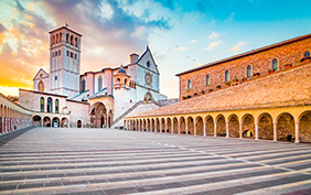 Famous Basilica of St. Francis of Assisi (Basilica Papale di San Francesco) with Lower Plaza at sunset in Assisi, Umbria, Italy