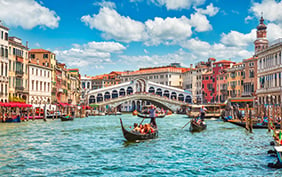 Bridge Rialto on Grand canal famous landmark panoramic view Venice Italy with blue sky white cloud and gondola boat water.
