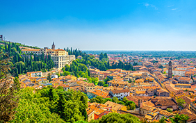 Aerial view of Verona historical city centre Veronetta, medieval buildings with red tiled roofs, cypress trees, blue sky background, Veneto Region, Italy. Verona cityscape, panoramic view.