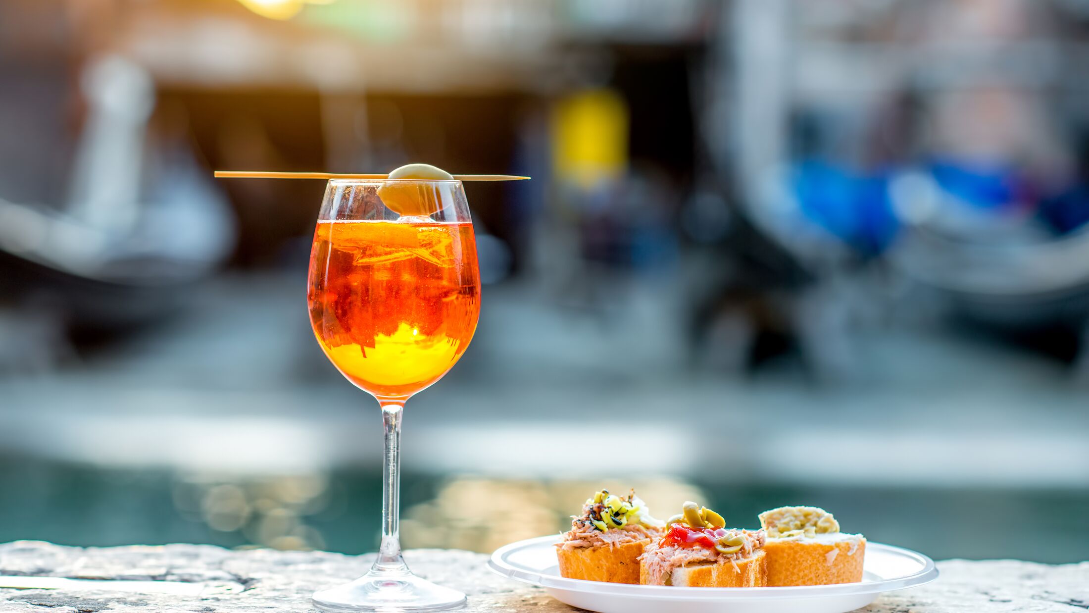 Spritz Aperol drink with venetian traditional snacks cicchetti on the water chanal background in Venice. Traditioanal italian aperitif. Image with small depth of field