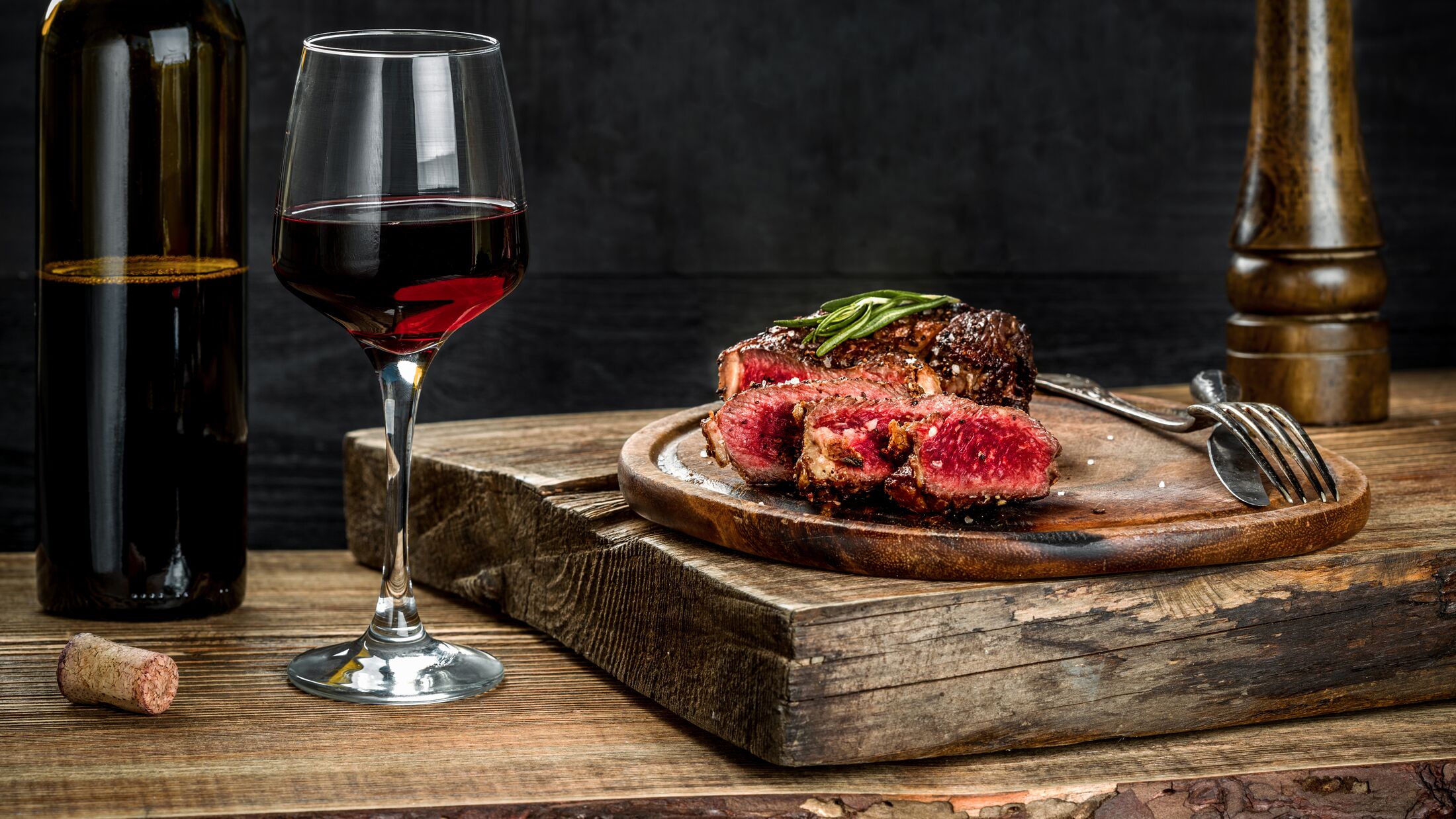 Grilled ribeye beef steak with red wine, herbs and spices on wooden table