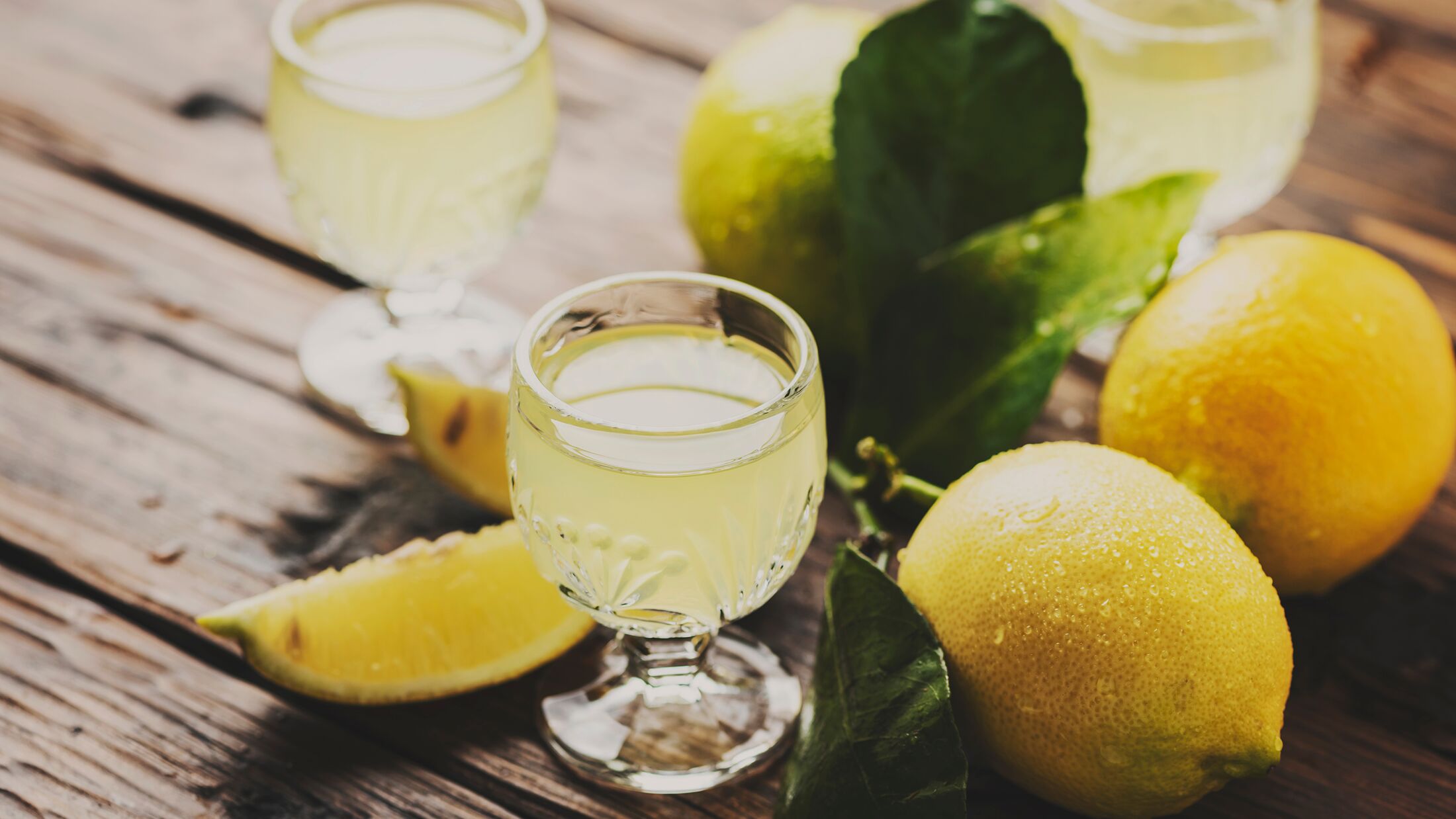 Italian typical digestive limoncello with fresh lemons, selective focus and toned image