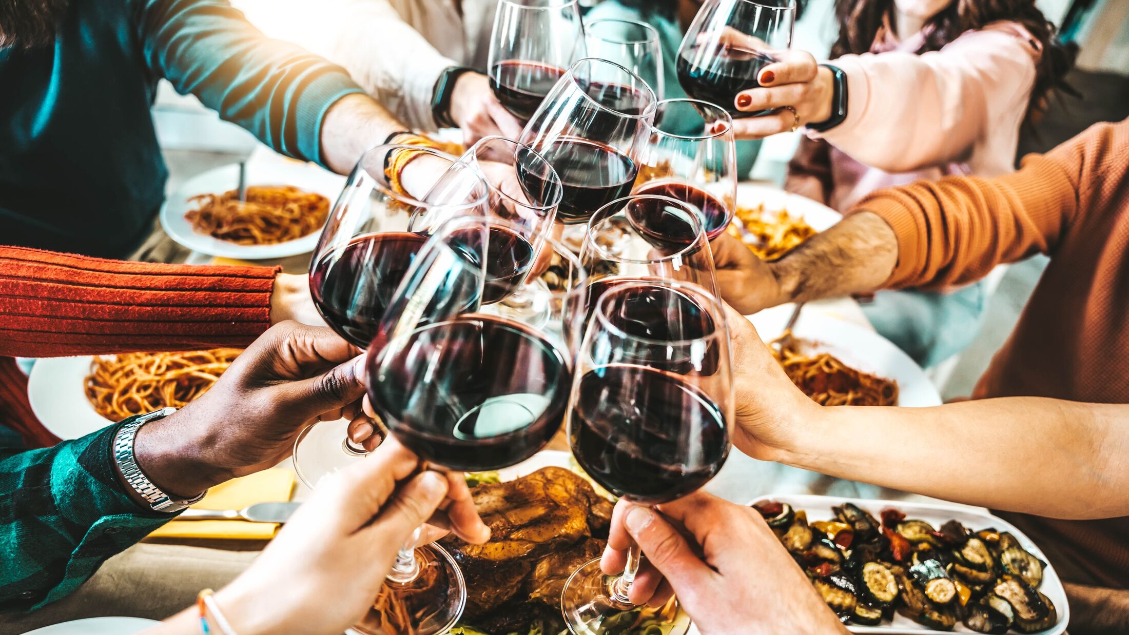 Happy friends toasting red wine glasses at dinner party - Group of people having lunch break at bar restaurant - Life style concept with guys and girls hanging out together - Food and beverage