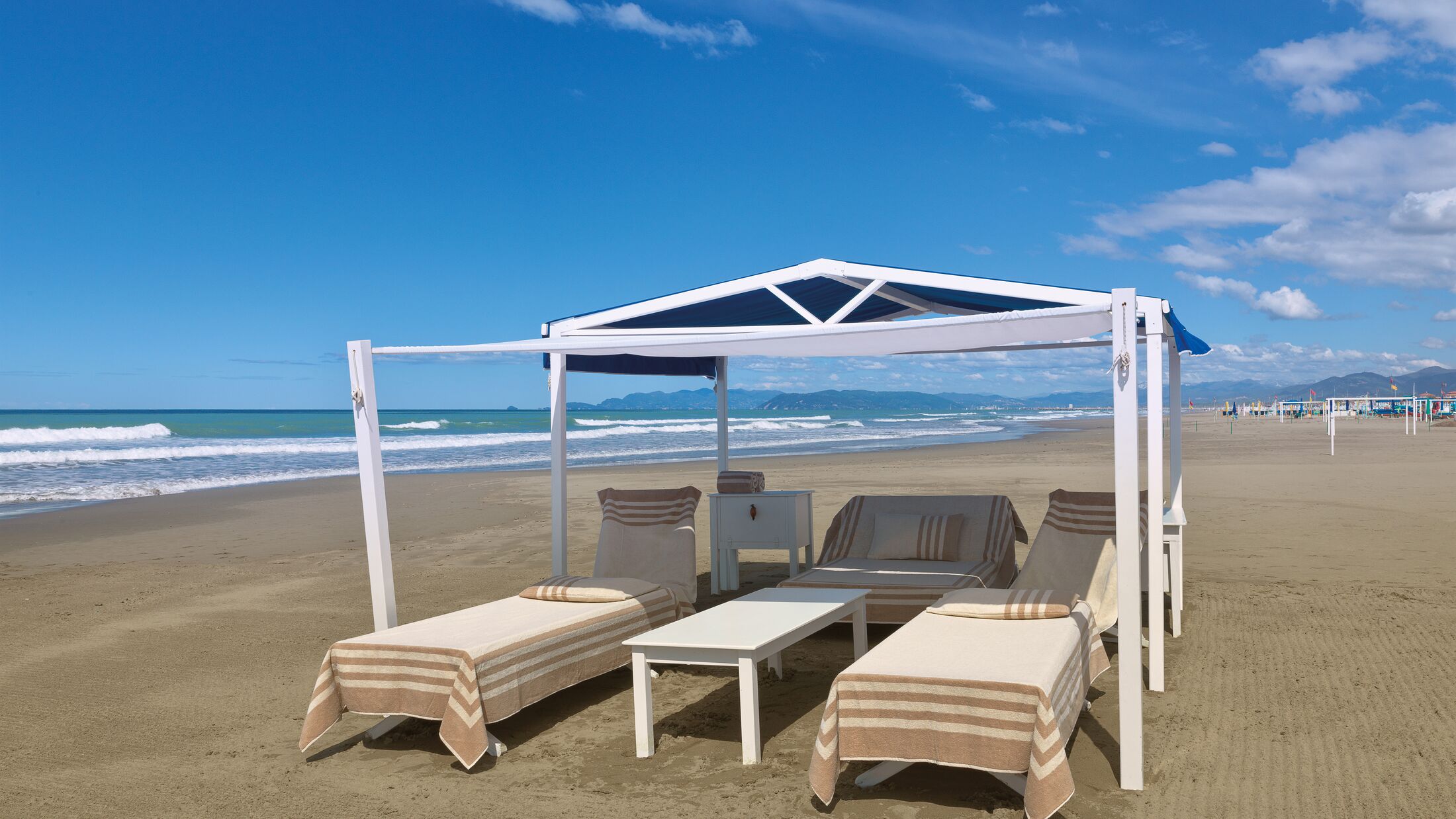 a couple of lawn chairs sitting on top of a sandy beach