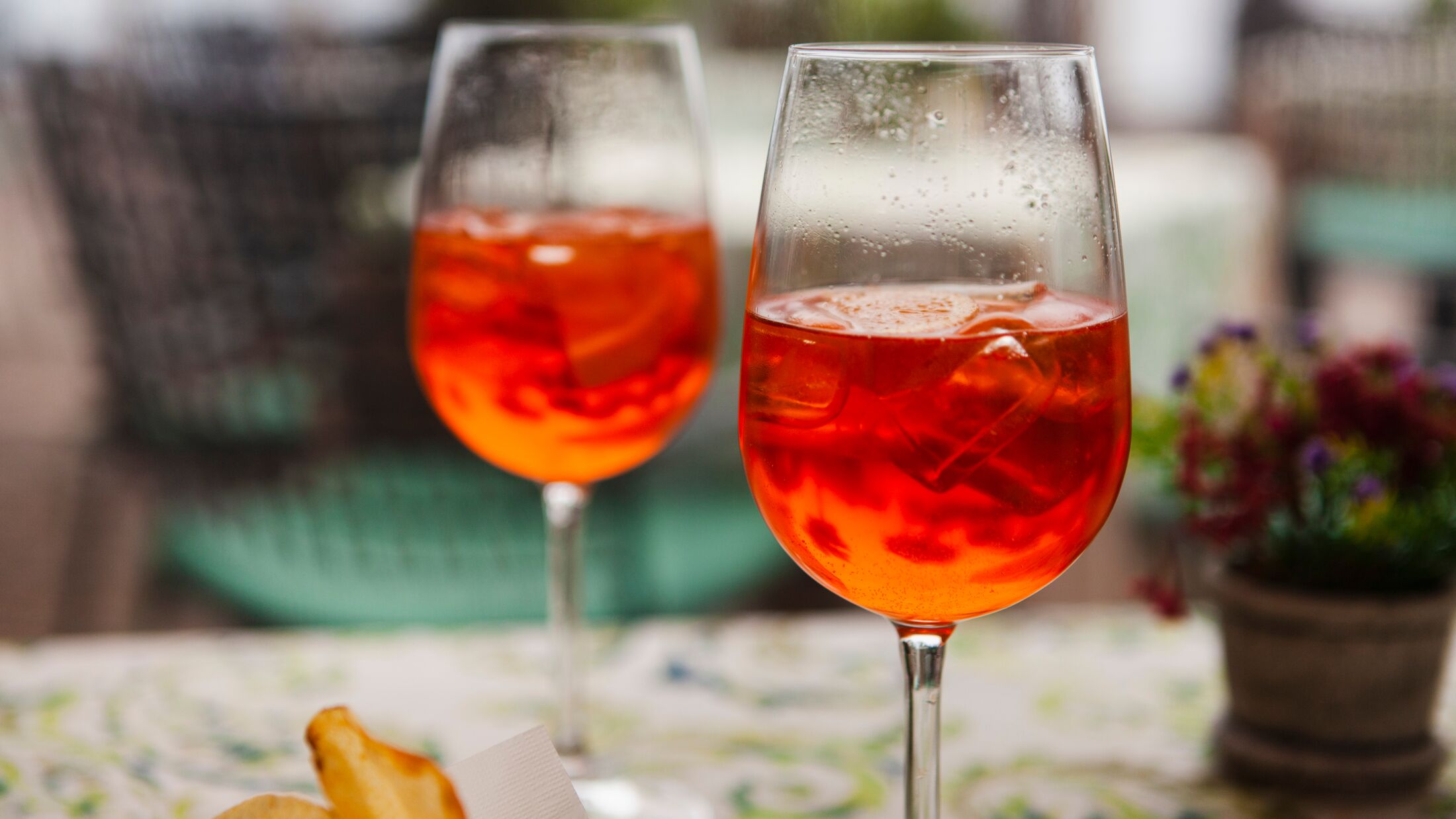 Italian traditional food and aperitif in the northern Italy, Lombardy, Milan. Two glasses of an alcoholic cocktail "Aperol spritz" with ice and snacks (potato chips) in an European cafe (restaurant).